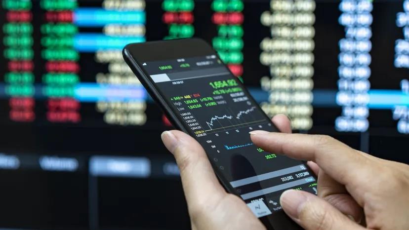 A Man Is Holding Mobile Phone With Charts Displayed