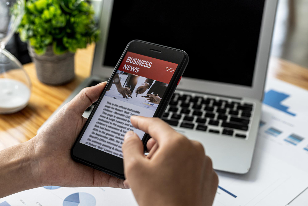 A Person Holding a Smartphone in Front of a News Website, Using a Smartphone To Read Online News 