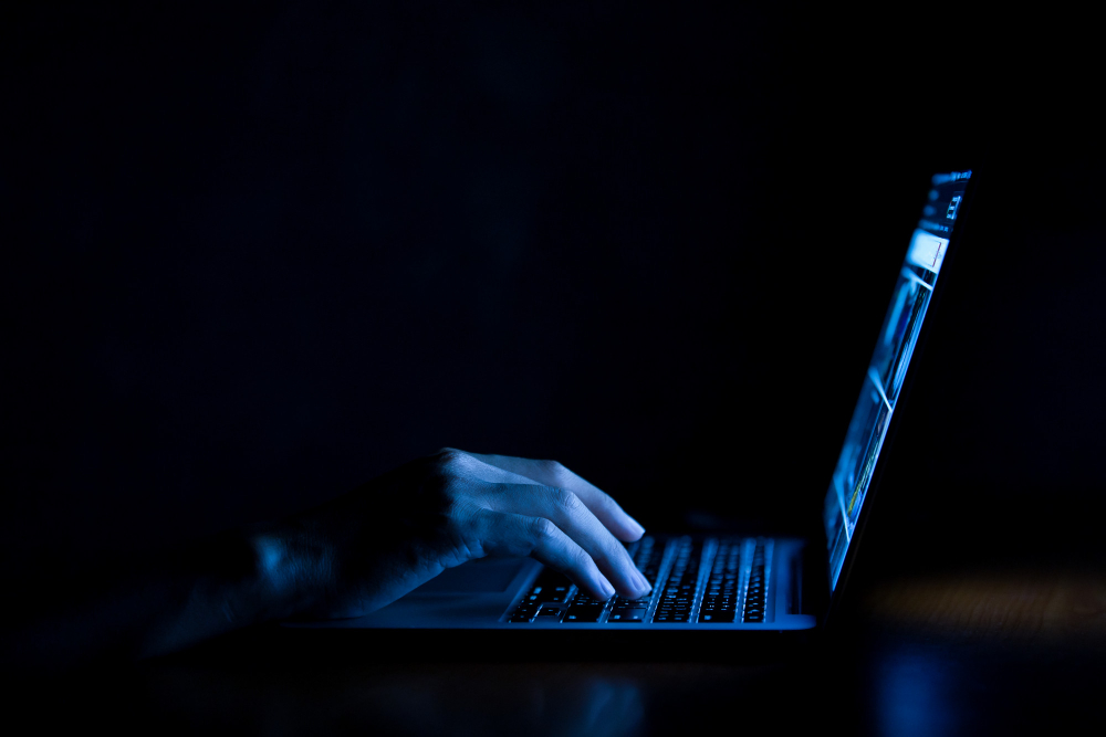 Hand of a Man Using Laptop Computer in the Dark