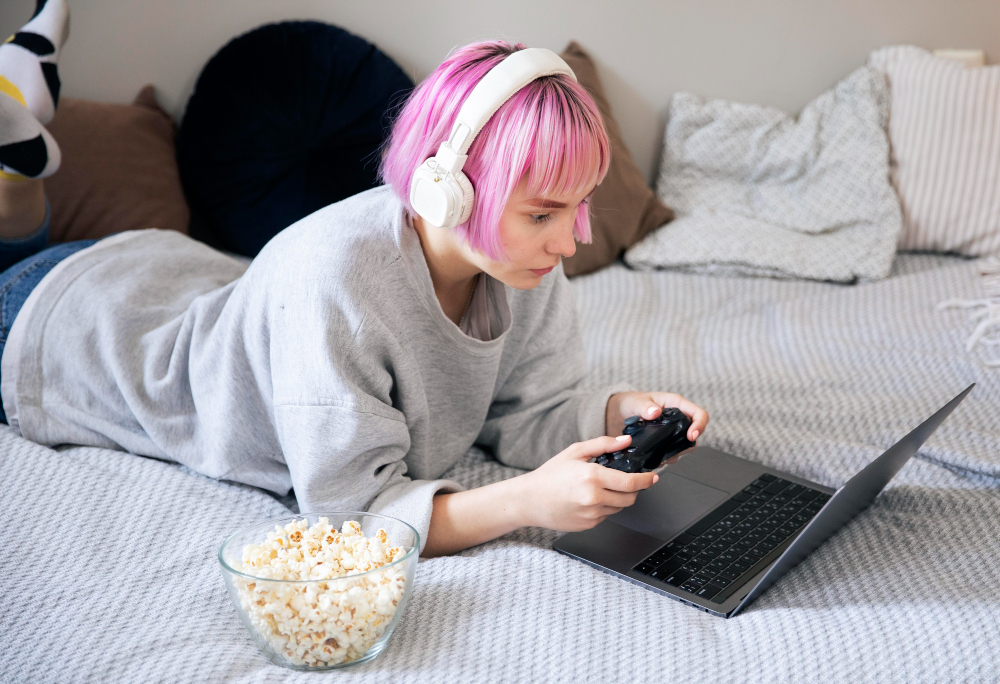 Young Woman With Pink Hair Playing With a Joystick on the Laptop