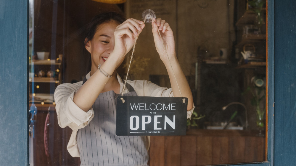 Young Manager Girl Changing a Sign From Closed To Open 