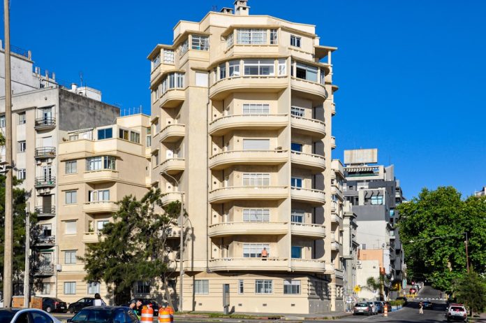 Tall cream-colored building with balconies under blue sky. montevideo cityscape, uruguay property, apartment buildings