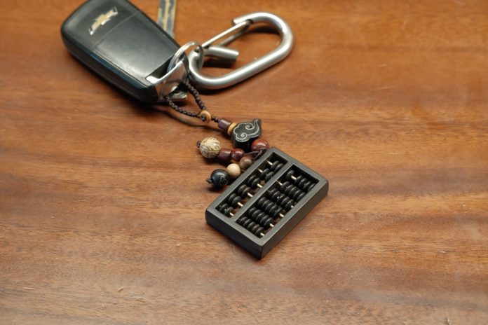Car key with an abacus charm rests on wood. remote access, mobile vpn, data encryption