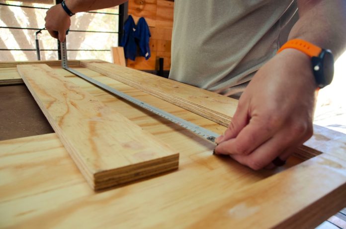 person in white shirt holding brown wooden table classroom carpentry workshop, students learning, diy tools