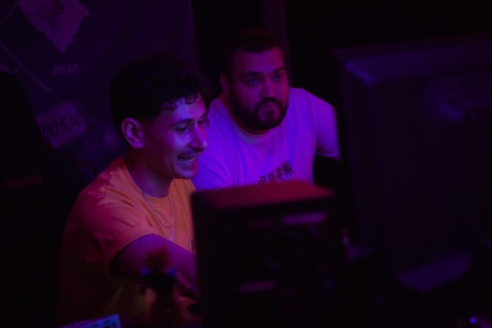 Two men looking at a computer screen gaming setup neon lights, online multiplayer screen, headset keyboard desk