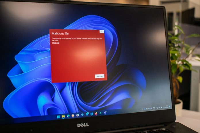 a dell laptop computer with a red screen windows defender warning screen, malware detection alert, windows security interface