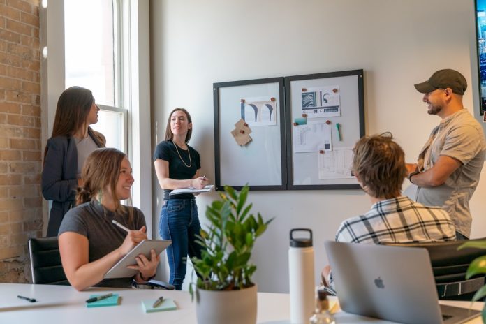 a group of people sitting around a table sales team meeting laptops charts modern office