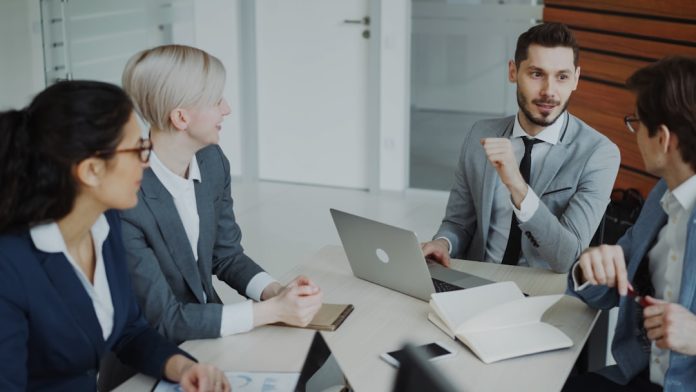 Four professionals in a business meeting around a table. sales team meeting laptops charts modern office