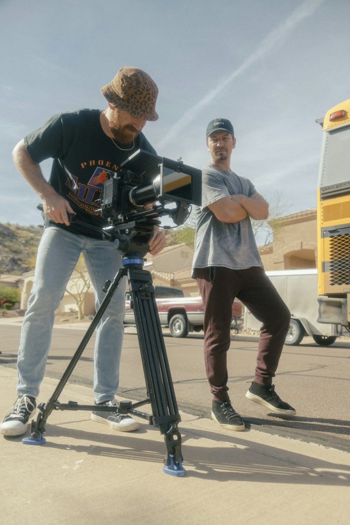 a couple of men standing next to a camera content creator editing video, social media video production, collaborative editing team
