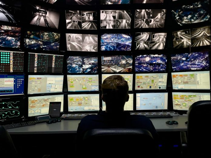 a man sitting in front of multiple monitors trader monitoring multiple screens energy market graphs control room