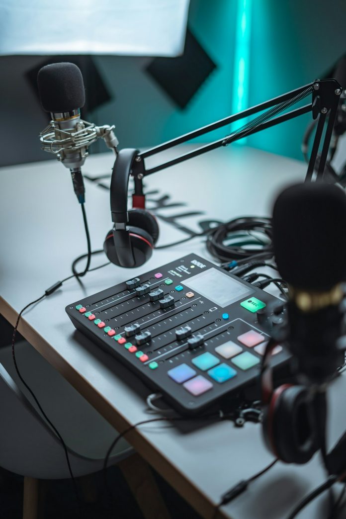 black and silver audio mixer audio waveform screen, podcast microphone setup, laptop audio editing software
