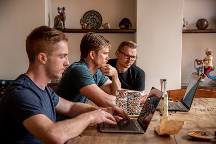man in blue crew neck t-shirt sitting beside woman in black tank top software team debugging session, developers looking at laptop, collaborative workspace