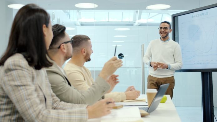 Man presenting to colleagues in a modern office setting enterprise team meeting, software evaluation discussion, business technology planning, corporate boardroom presentation