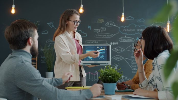 Woman presenting a business strategy to colleagues enterprise team meeting, software evaluation discussion, business technology planning, corporate boardroom presentation
