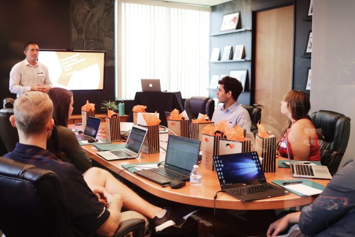 man standing in front of people sitting beside table with laptop computers incident response, cybersecurity planning, executive meeting
