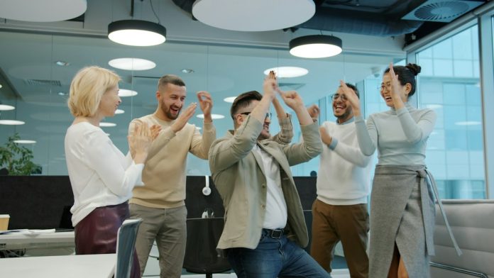 Diverse group of colleagues celebrating success in office sales team, leaderboard, office competition