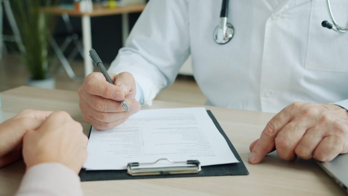 Doctor writing on a patient's chart dentist writing blog, dental education, patient trust