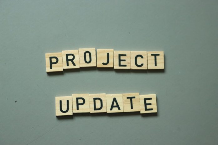 two scrabble tiles spelling project update on a table manager approval, office workflow, project decision