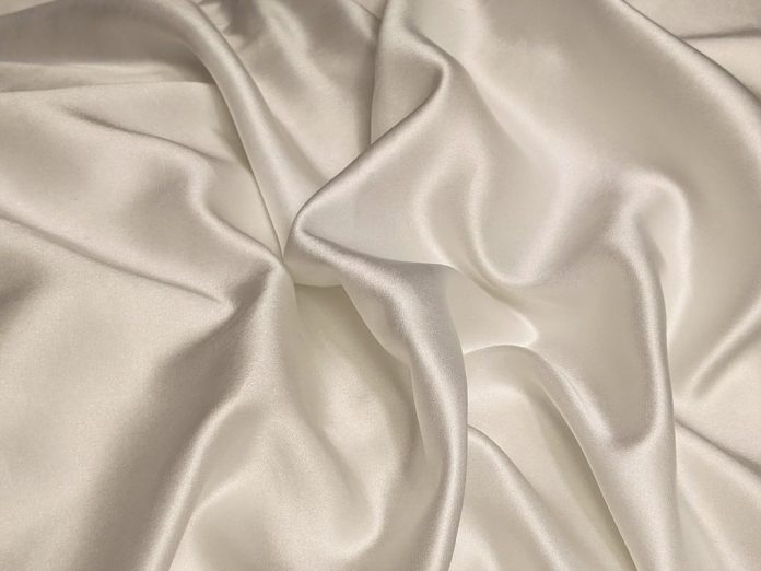 white textile on brown wooden table viscose fabric, soft drape, flowing garment
