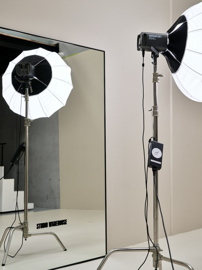Two studio lights with white umbrellas on metal stands in a bright room female portrait, softbox fill, studio reflector
